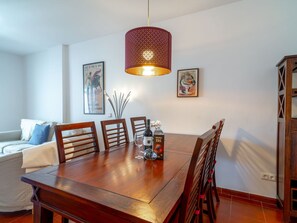 A dining area with a wooden table, chairs, a hanging light fixture, and two framed artworks on the wall. - Apartment  by Interhome (Nerja)