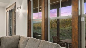Ein modernes Wohnzimmer mit einem großen Fenster, einer Couch und einem Tisch mit Stühlen.