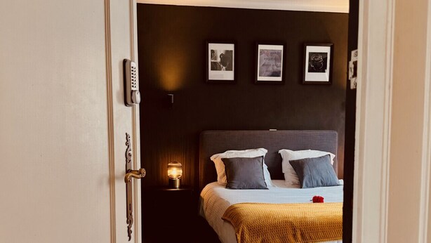 Ein Schlafzimmer mit Bett, Nachttisch, an der Wand befestigten Bildern und einer Tür.