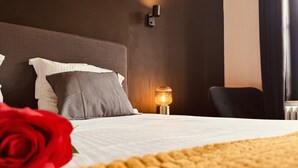 Ein ordentlich bezogenes Bett mit einer weißen Decke und einer einzelnen roten Rose auf der linken Seite.