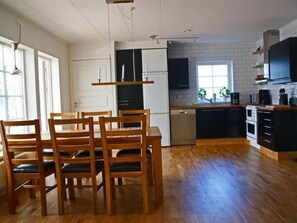 A modern kitchen with wooden chairs, a dining table, a dishwasher, and a built-in oven. - Gemütliches Holzhaus Udden mit eigenem Boot by Interhome (Sexdrega)