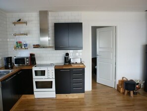 A compact kitchen with white cabinets, a microwave, a coffee maker, and a stove. - Gemütliches Holzhaus Udden mit eigenem Boot by Interhome (Sexdrega)