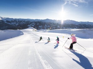 Pistes d'esquí amb esquiadors, muntanyes al fons i un cel serè.