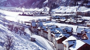 A snow-covered mountain town with traditional chalet-style buildings, a river, and mountains in the background. - Apartment  by Interhome (Rauris)