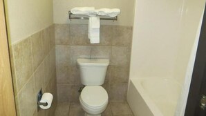 A bathroom with a toilet, a towel rack with towels, a toilet paper holder, and a bathtub. - Super Davneport Inn & Suite (Davenport)