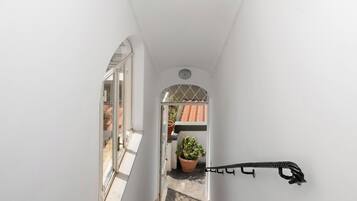 Una stretta scala con corrimano che conduce a un balcone con una pianta in vaso.