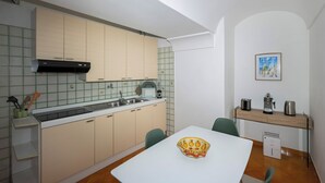 A compact kitchen with a white table, a sink, and a stove. - De Vivo Realty - The Colombo Positano (Positano)