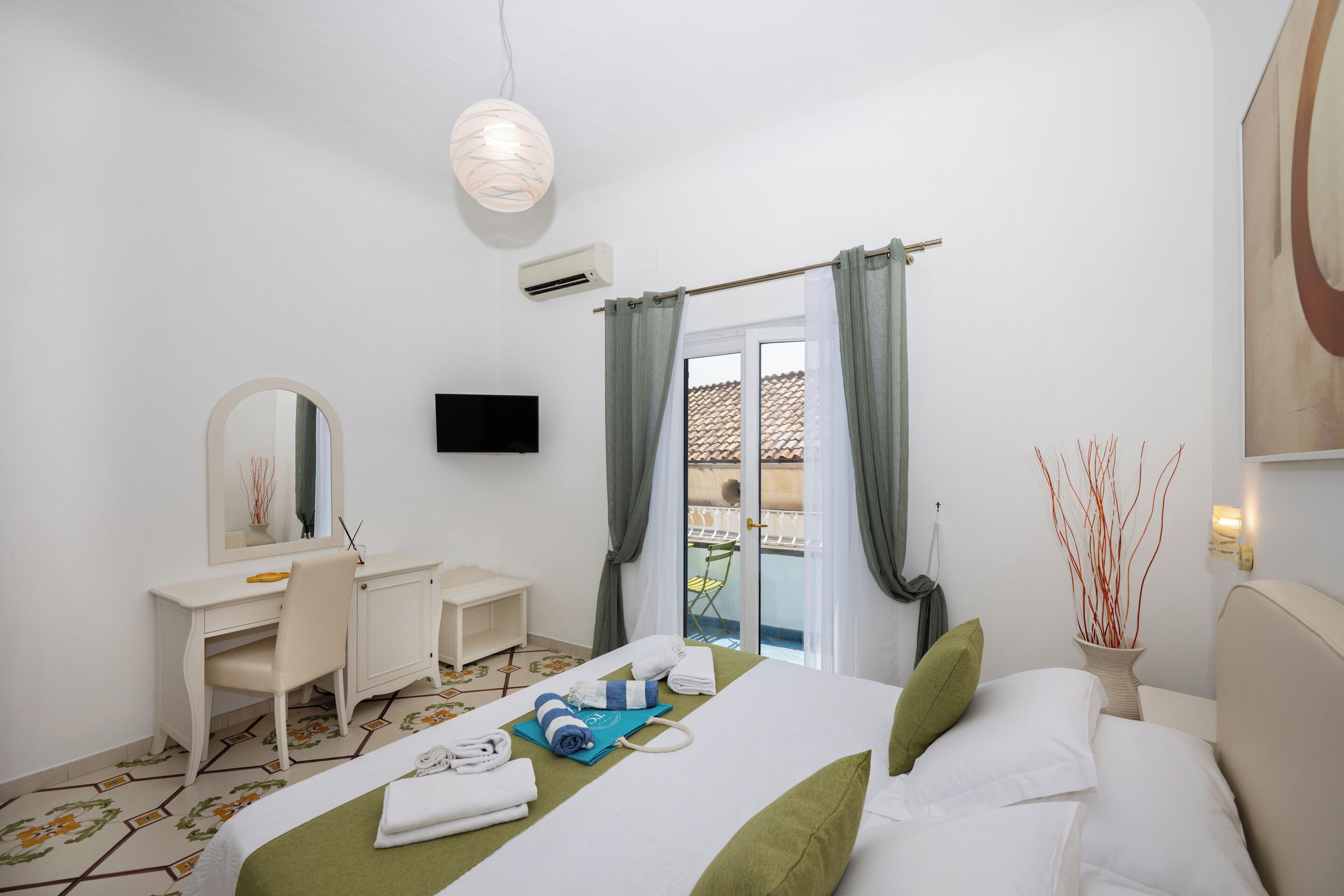 A hotel room with a bed, a desk, a chair, a television, and a view of the outside.