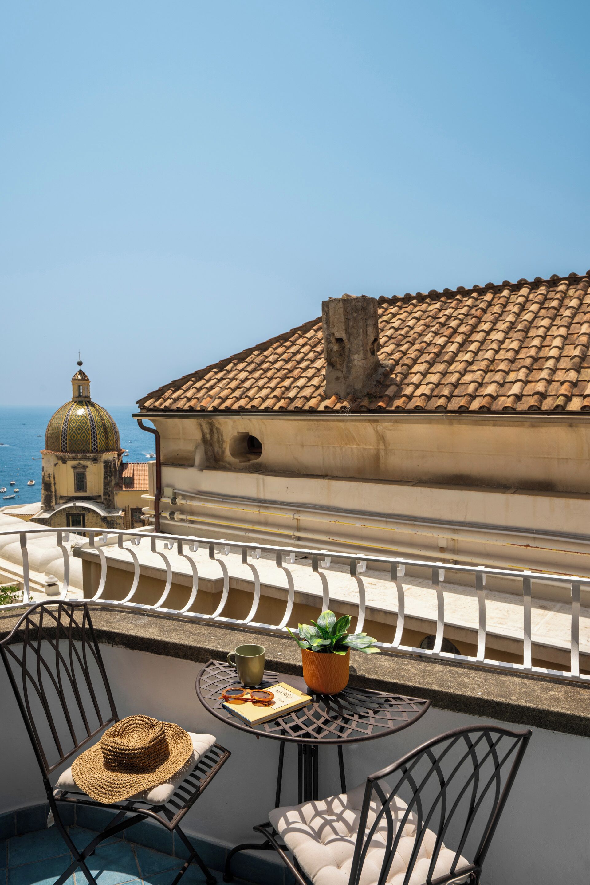 Un balcon avec vue sur la mer, un bâtiment doté d’un toit en tuiles et du mobilier d’extérieur.