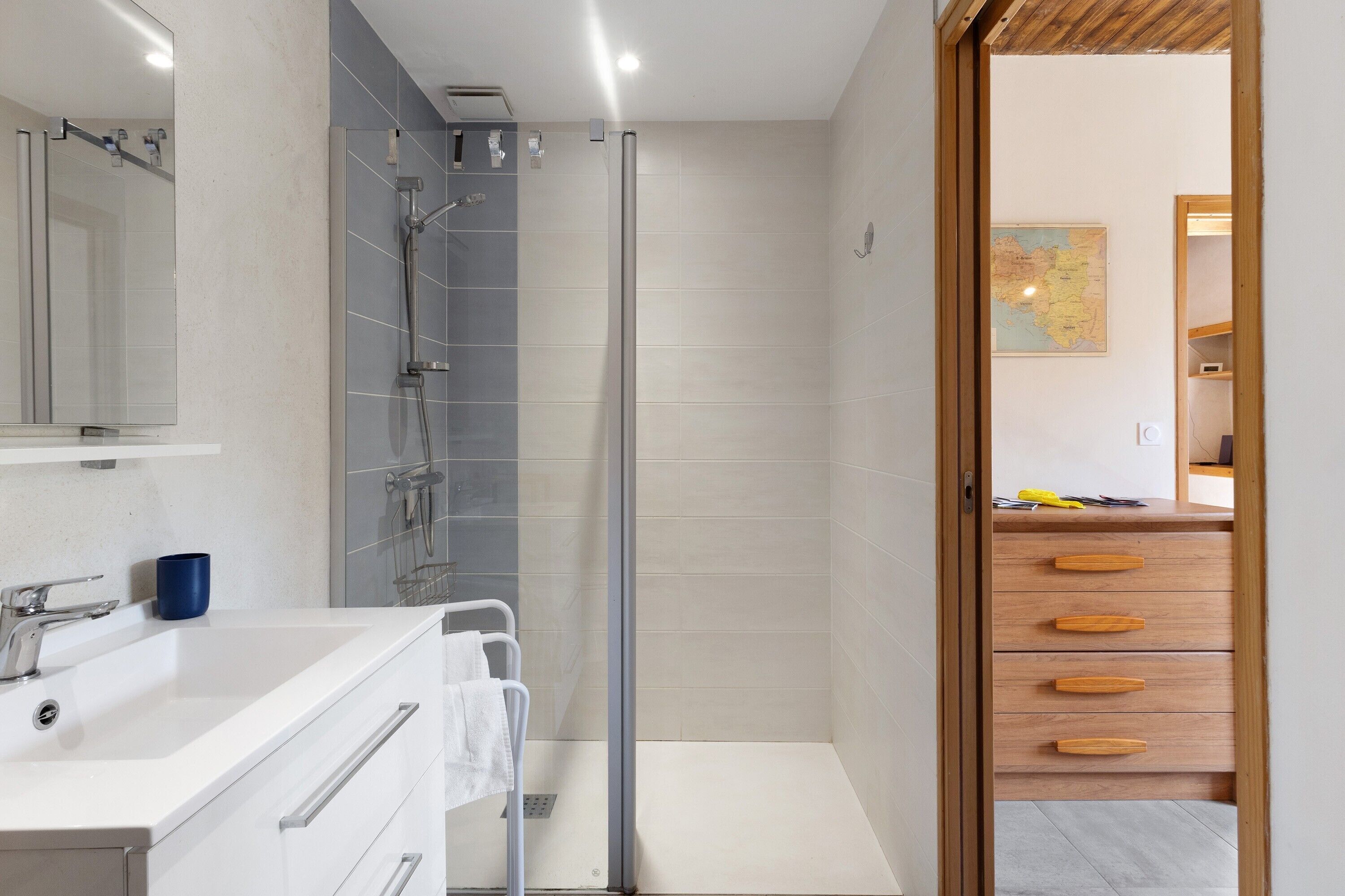 Une salle de bain moderne avec une douche, un lavabo et un miroir.