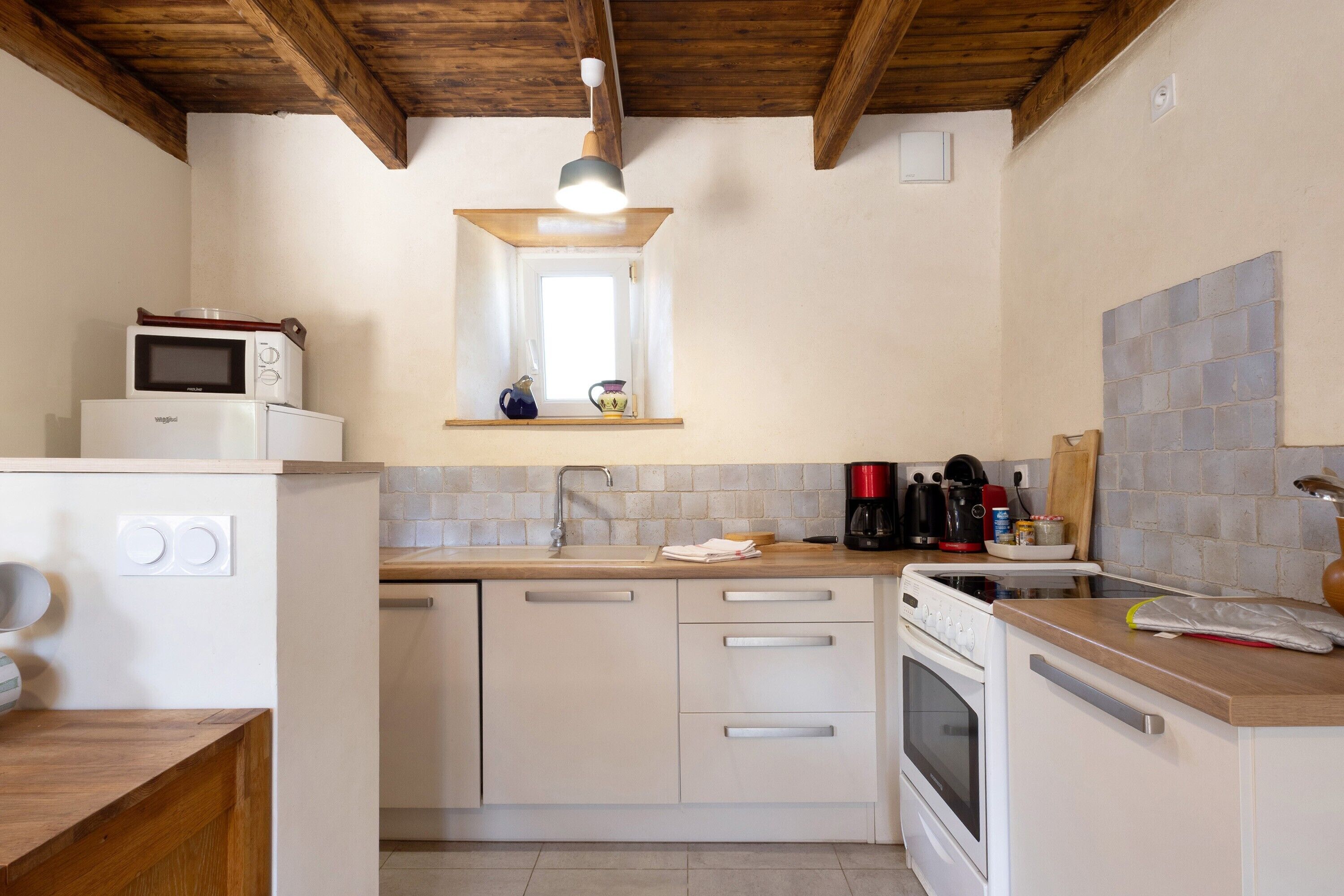 Een kleine keuken met een magnetron, fornuis en spoelbak.