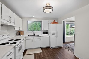Una cocina moderna con armarios blancos, estufa, microondas y refrigerador.