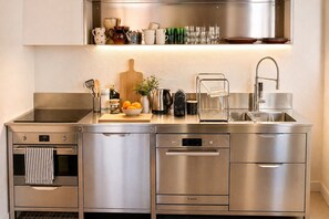 Una cocina moderna con electrodomésticos de acero inoxidable, una cafetera y una variedad de utensilios de cocina.
