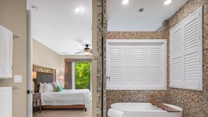 Ein Hotelzimmer mit Bett, Badezimmer mit Badewanne und Blick auf Grün.