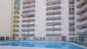 Un immeuble résidentiel à plusieurs étages, doté de balcons, d’une piscine et d’une entrée sécurisée.