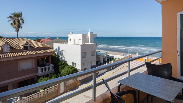Un balcon avec vue sur la mer, une table et des chaises.
