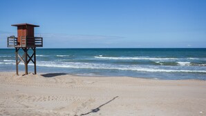 Une tour de surveillance des sauveteurs sur une plage de sable, avec l’océan en arrière-plan.