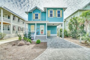 A two-story house with a covered porch, a front door, and a small front yard with plants. - Dogs Welcome | Communal Pool Access (Port St. Joe)