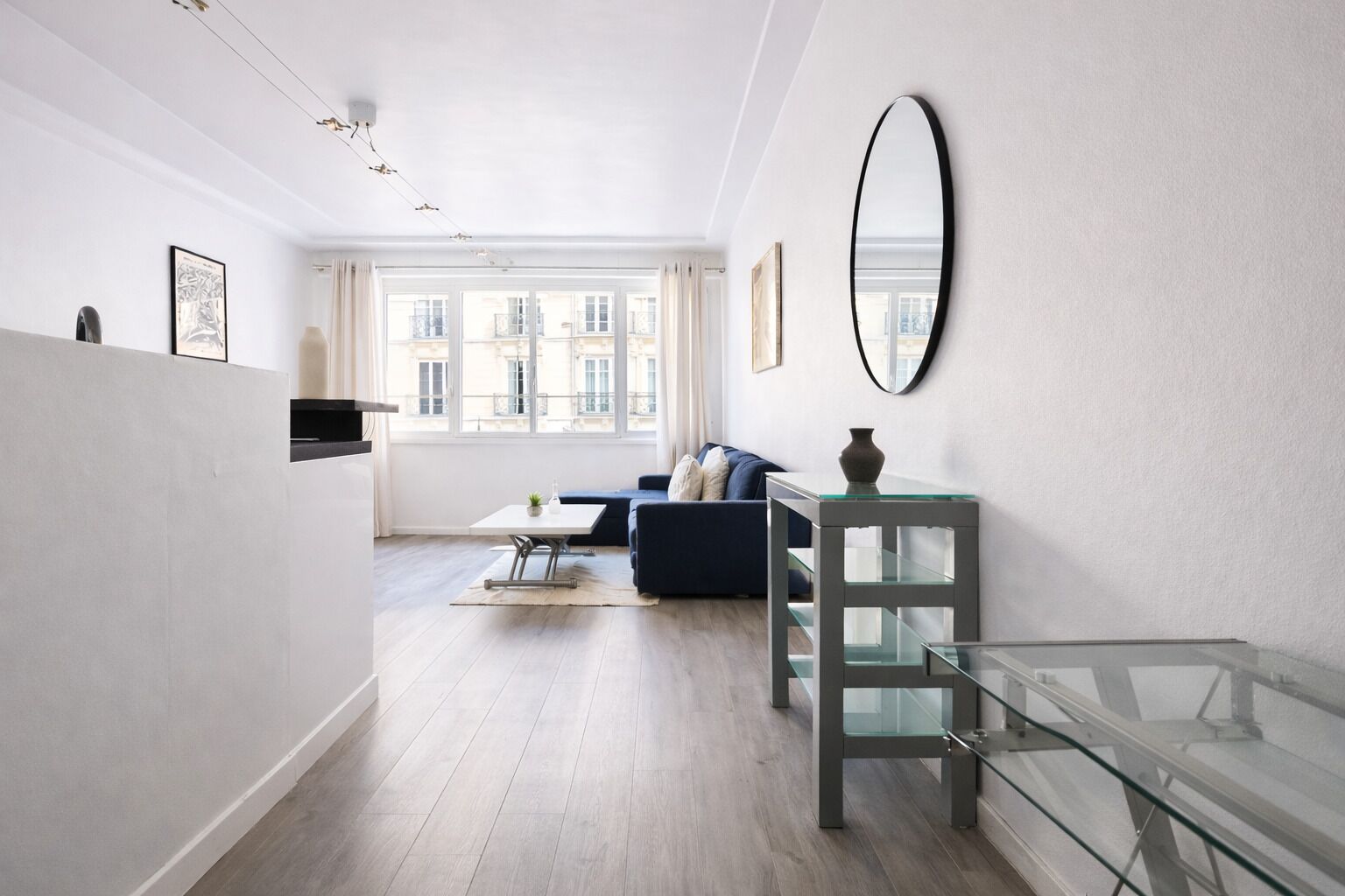 A modern living room with a sofa, a glass coffee table, and a minimalist side table.