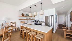 Una cocina moderna con una isla grande, sillas de madera y lámparas colgantes.