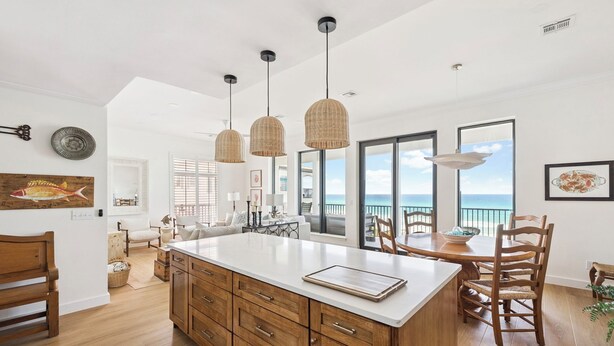 Una cocina amplia con una isla grande, armarios de madera e iluminación colgante.