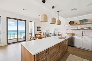 A modern kitchen with a large island, pendant lights, and a view to the beach. - Newly Listed Beach Front Condo with Community Pool Access and Elevator (Santa Rosa Beach)