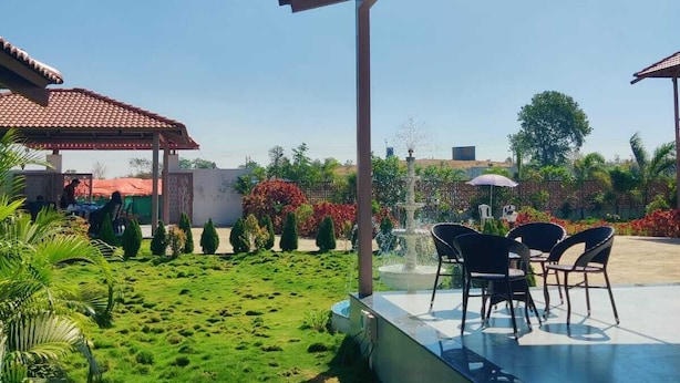 A covered outdoor area with a fountain, seating, and a well-maintained garden.