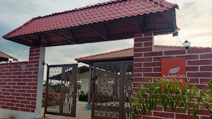 A gated entrance with a red-tiled roof, a decorative metal gate, and a sign with a leaf symbol.