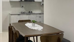 Una cocina moderna con armarios blancos, estufa integrada y comedor con mesa y sillas de madera.