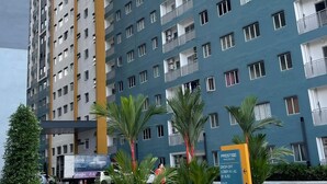 Un edificio residencial de altura con varios balcones, zona de estacionamiento y un cartel que indica los servicios.