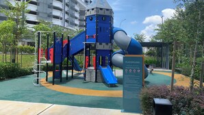Un parque infantil con un tobogán, estructuras para escalar y una casita.