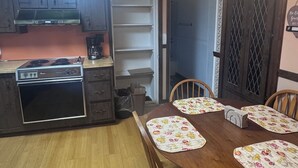 A kitchen with a stove, cabinets, and a dining table with chairs. - Inviting 1BR Near Boston -- Easy Transit -- Parking Included (Malden)