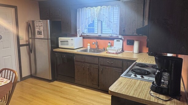 A compact kitchen with a refrigerator, microwave, sink, and stove. - Inviting 1BR Near Boston -- Easy Transit -- Parking Included (Malden)