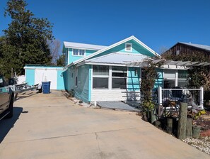 Ein zweigeschossiges Haus mit blauer Fassade, einer Garage und einer Auffahrt.