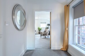 A hallway with a mirror, a door leading to a room, a window with a curtain, and a chair in the background. - Old Dutch Embassy by Guestz (Hull)