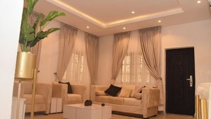 Ein Wohnzimmer mit einem beigefarbenen Sofa, einem weißen Couchtisch und einer Zimmerpflanze.