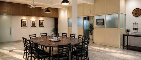 Un espace repas avec une table ronde, des chaises, des luminaires suspendus et une cuisine en arrière-plan.