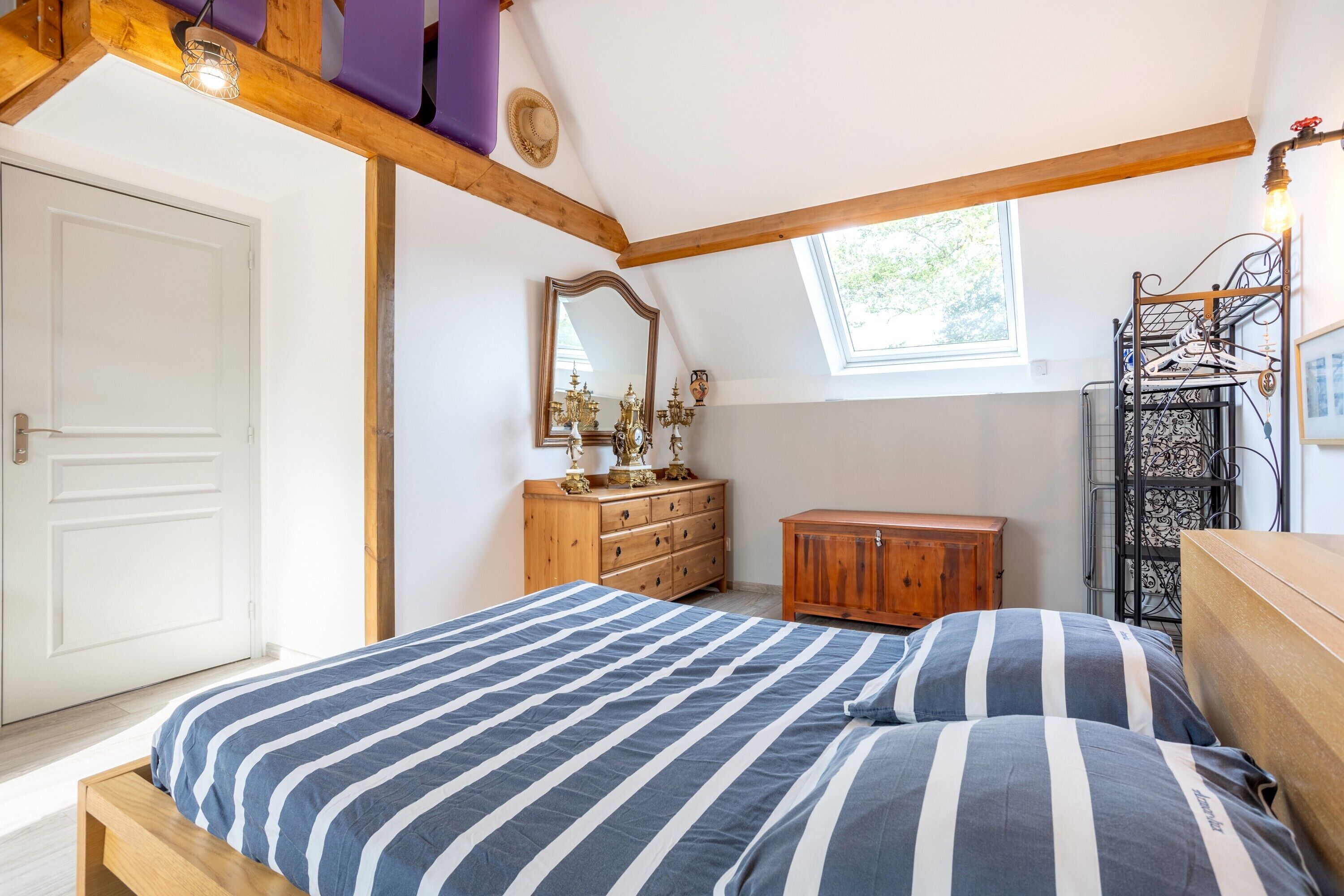 A bedroom with a bed, wooden dresser, and a mirror.