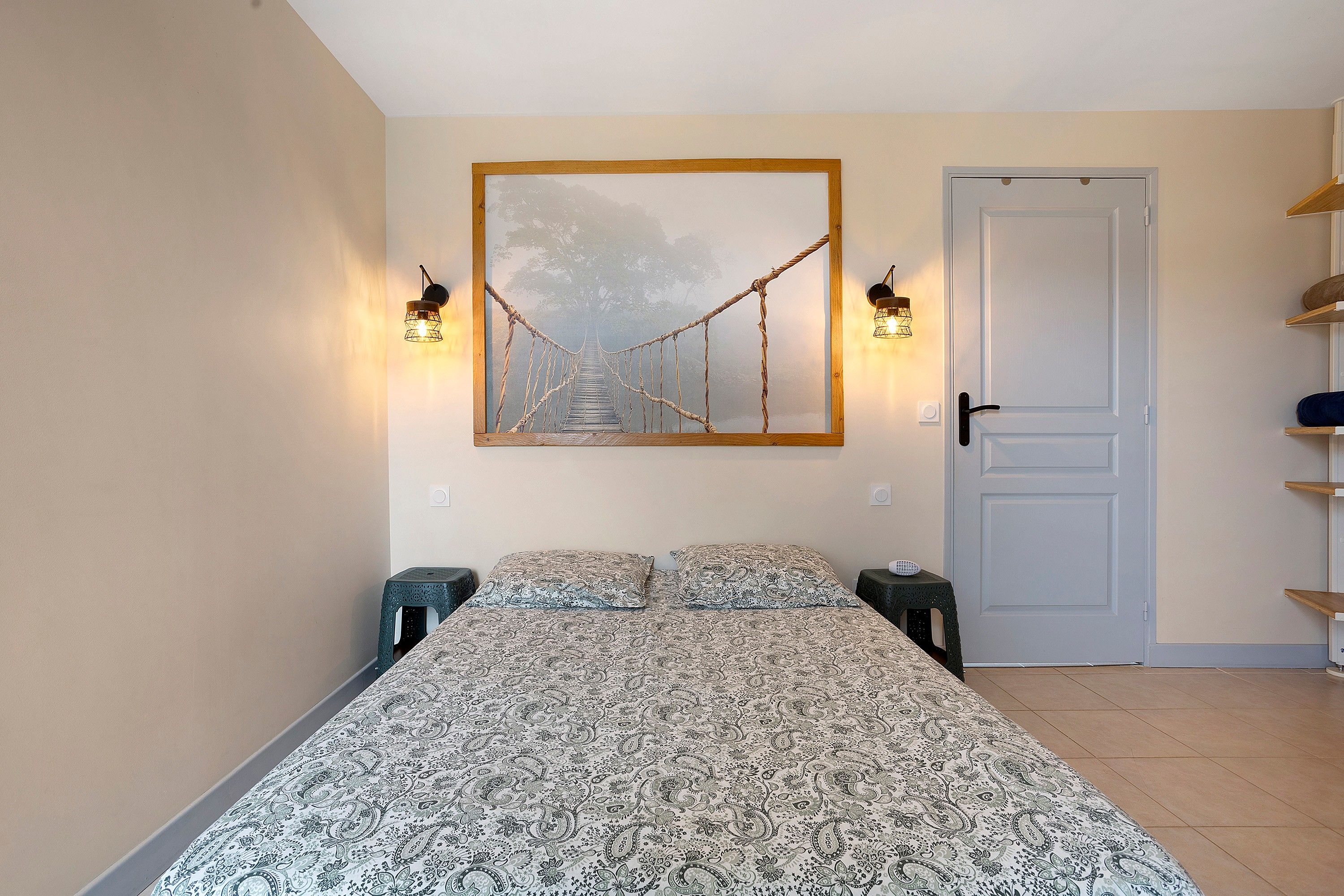 Une chambre à coucher avec un lit, une porte et un tableau accroché au mur.