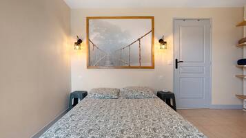 Une chambre à coucher avec un lit, une porte et un tableau accroché au mur.