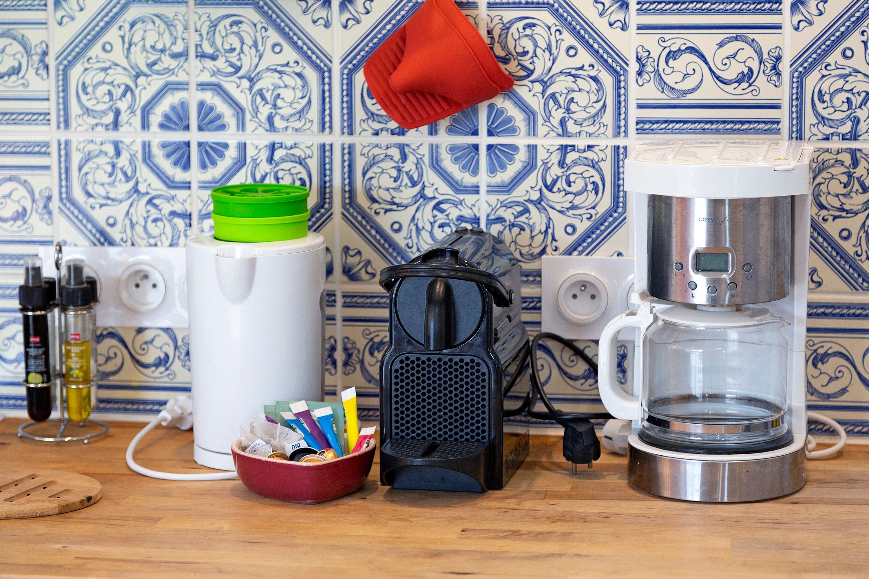 A kitchen with a coffee maker, a kettle, and a mug on the counter.