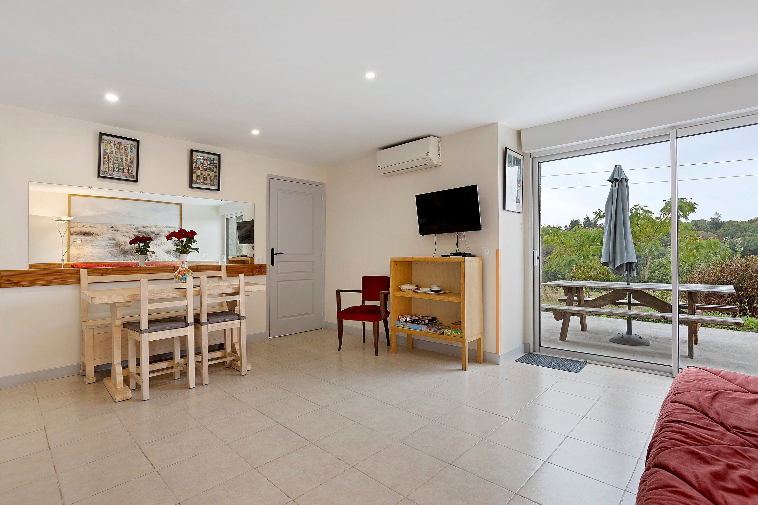 A room with a dining table, chairs, a television, and a sliding glass door leading to an outdoor area.