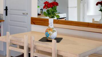 A dining table with a vase of red flowers and a decorative bowl with floral patterns.