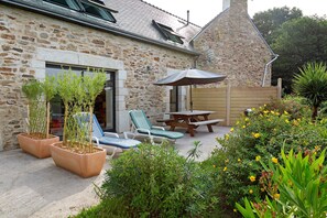 A stone building with a patio area featuring outdoor seating and a table.