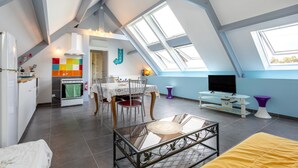A loft-style room with a dining area, kitchenette, and a TV.