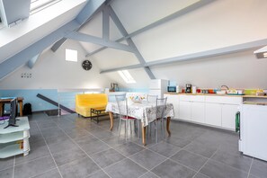 Una cocina moderna con comedor, un reloj en la pared y una escalera que sube a un nivel superior.