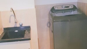 Una cocina compacta con un lavabo, un refrigerador pequeño y una lavadora.