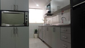 Una cocina moderna con microondas integrado, electrodomésticos de acero inoxidable y armarios grises.
