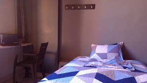 Un dormitorio con una cama, un escritorio y una silla.