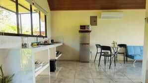 Une cuisine compacte équipée d’un réfrigérateur, d’un four à micro-ondes et d’un coin repas avec des chaises et une table.